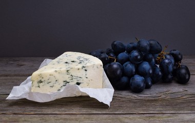 Blue cheese/Roquefort with fresh grape on white paper. Fruits, cheese, top view. Delicacy food.
