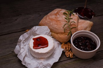 Fresh bread, Camembert cheese and cowberry jam served on a vintage styled dark wooden table. Menu design horizontal