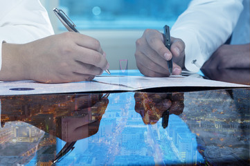 Businessmen hands signing documents on Riyadh skyline city scape background