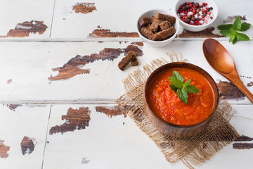 Tomato soup in a wooden bowl with pieces of toast on a rustic table.