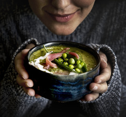 Woman holding a bolw filled with green pea soup