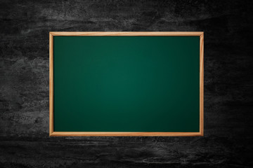 Empty green chalkboard or school board background and texture with wood frame on the black wall, education and back to school concept.