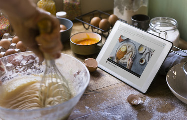 Woman whisking while looking at a recipe on a tablet