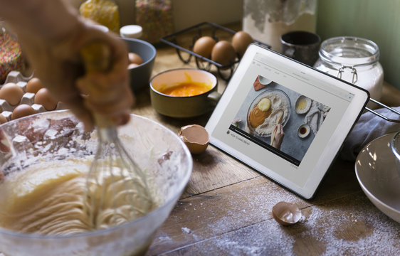 Woman whisking while looking at a recipe on a tablet - Powered by Adobe