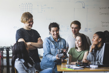 Teacher examining science project in classroom