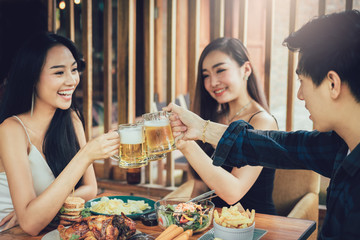Teenager asian people having fun at drinking with cheering with beer at restaurant.