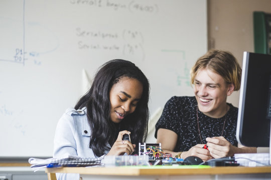 Smiling students preparing science project in classroom