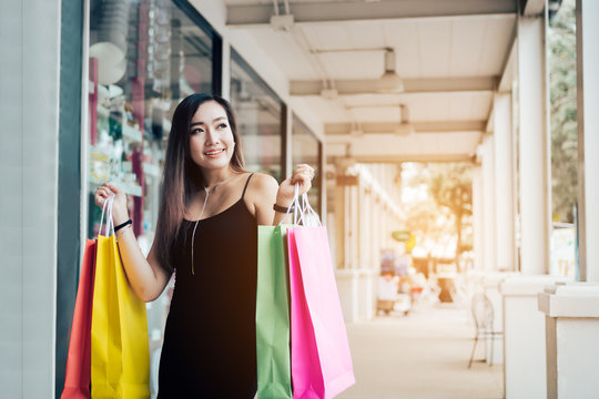 Asian funny woman holding shopping bags.