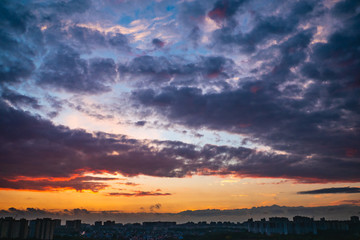 Dramatic colorful autumn clouds at sky over city at sunset, beautiful nature landscape panorama