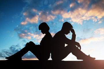 Silhouette Of Sad Couple Sitting Back To Back