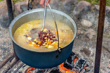Cooking food in a pot on campfire. Summer camping concept.