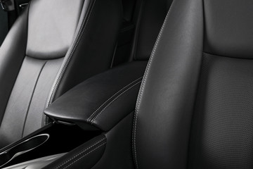 Modern luxury car black leather interior. Part of leather car seat details with stitching. Interior...