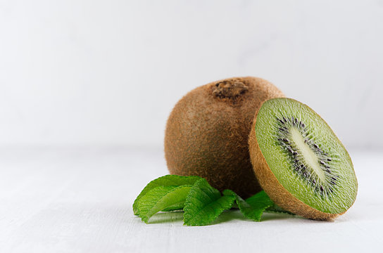 Juicy fresh kiwi with slice, leaves closeup on white wooden background, copy space, closeup. Elegance light soft fruits backdrop.