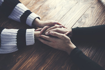 Naklejka premium man and a woman holding hands at a wooden table