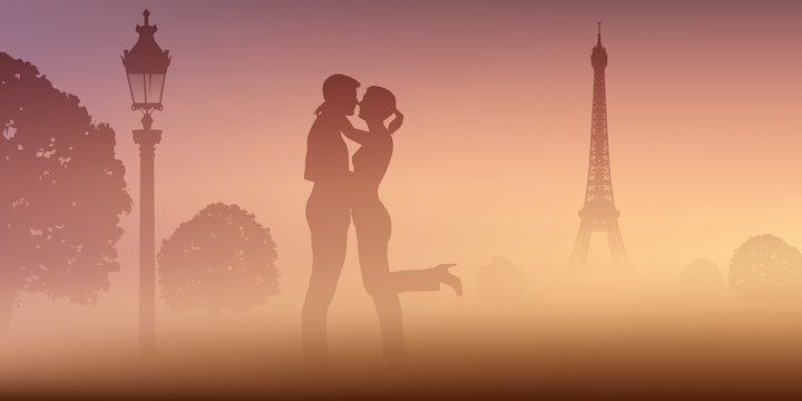 A Paris, un un couple d'amoureux au Champ de mars, s'embrassent devant la Tour Eiffel par un matin de brume