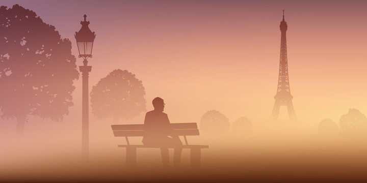 A Paris, un homme médite seul au Champ de mars, assis sur un banc devant la Tour Eiffel par un matin de brume