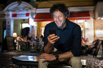 Mature happy man using phone at night