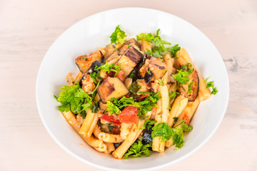 Italian food - Sicilian pasta with eggplants in a white plate on a light rustic wooden table