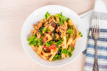 Italian food - Sicilian pasta with eggplants in a white plate on a light rustic wooden table