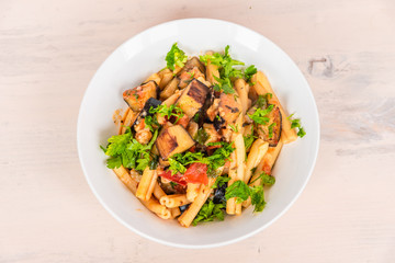 Italian food - Sicilian pasta with eggplants in a white plate on a light rustic wooden table