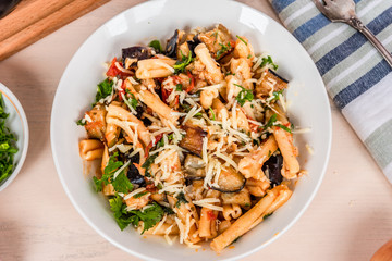 Vegetarian Italian pasta with eggplants, top view, a plate with pasta on a light rustic table with a napkin