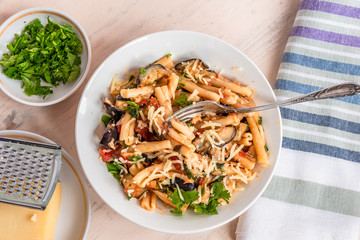Vegetarian Italian pasta with eggplants, top view, a plate with pasta on a light rustic table with a napkin