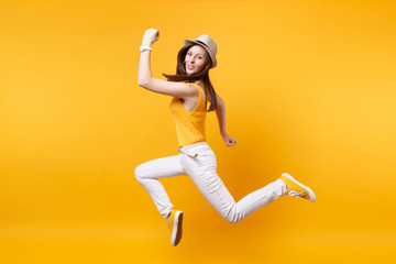 Fototapeta na wymiar Portrait of excited smiling young happy jumping high woman in straw summer hat, copy space isolated on yellow orange background. People sincere emotions, passion lifestyle concept. Advertising area.