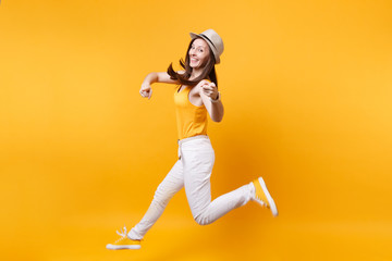 Fototapeta na wymiar Portrait of excited smiling young happy jumping high woman in straw summer hat, copy space isolated on yellow orange background. People sincere emotions, passion lifestyle concept. Advertising area.