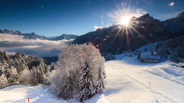 Beautiful 4k UHD timelapse video of the sun and clouds at sunrise in the Brandnertal in the mountains of the Alps in Vorarlberg, Austria, in winter with snow