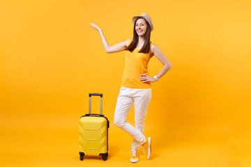 Fototapeta na wymiar Traveler tourist woman in summer casual clothes, hat with suitcase isolated on yellow orange background. Female passenger traveling abroad to travel on weekends getaway. Air flight journey concept.