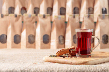 Glass of hot tea and wooden spoon with dried tea leaves.