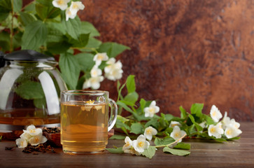 Green tea with jasmine in cup and teapot on old wooden table.
