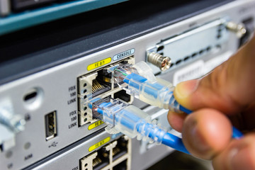 Closeup hand man connection red cable network connection to Network switch in rack, network cables...