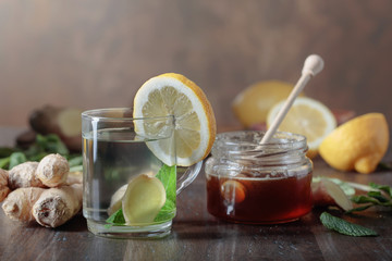 Ginger tea with honey , lemon and mint on old wooden table .