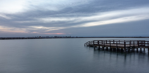 Fototapeta na wymiar Long exposure of wooden pier at sunrise with lake