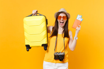 Traveler tourist woman in summer casual clothes, hat with suitcase, passport, ticket isolated on yellow orange background. Girl traveling abroad travel on weekends getaway. Air flight journey concept.