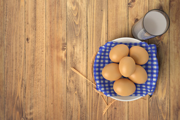 Render of eggs on blue towel in ceramic bowl on wooden table with glass of milk. Isolated on white background.
