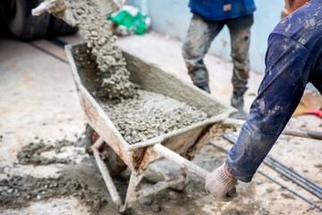 Concrete mixed cement pouring from mortar grinder truck to trolley, holding by worker