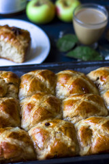 Hot cross buns with the cup of coffee, cinnamon sticks on the table