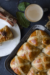 Hot cross buns with the cup of coffee, cinnamon sticks on the table flat lay