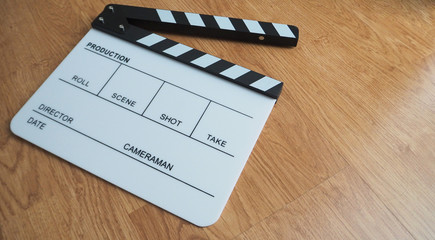 Clapper board or movie slate use in video production or movie and cinema industry. Put on wood background.