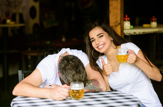 Best Friends Or Lover Drink Beer In Pub. Couple In Love On Date Drinks Beer. She Knows Tricks How To Drink And Stay Sober. Man Drunk Fall Asleep On Table And Girl With Full Beer Glass. Enough For Him