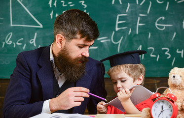 Father with beard, teacher teaches son, little boy. Individual schooling concept. Kid studies...