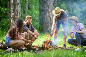 Roasting marshmallows popular group activity around bonfire. Company friends prepare roasted...