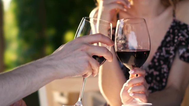 Cropped video closeup of young loving couple sitting outdoors drinking wine
