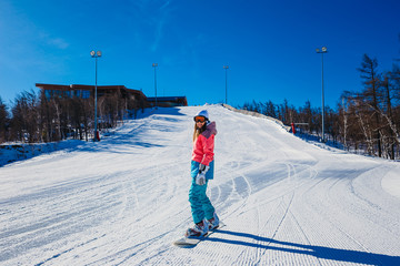 a young woman comes down from the mountains on a snowboard