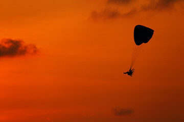 Fototapeta na wymiar Silhouette of paramotor flying at during the sunset