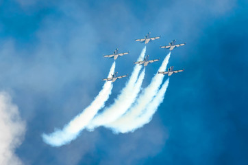 Group of fighter jet planes fly and leave behind a white smoke trail.