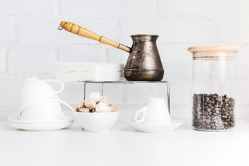 Coffee drink concept. Coffee cups, jezve, coffee beans, sugar cubes, cane sugar, white sugar and white porcelain cups.