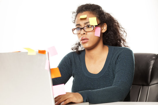 Confused young african woman with stickers on her head and comuter on white background